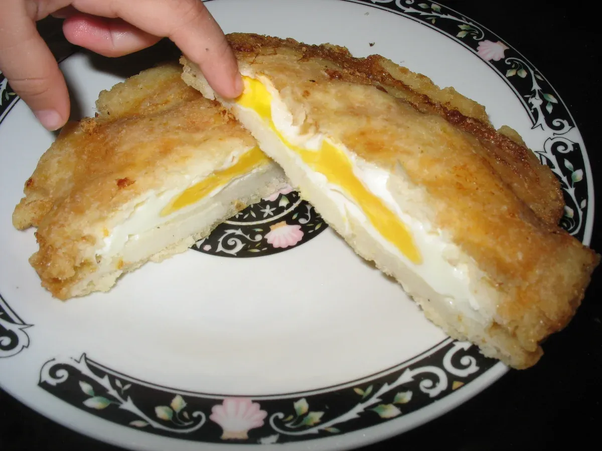 A split arepa de huevo showing the egg cooked inside the fried corn dough, on a Cartagena, Colombia city guide
