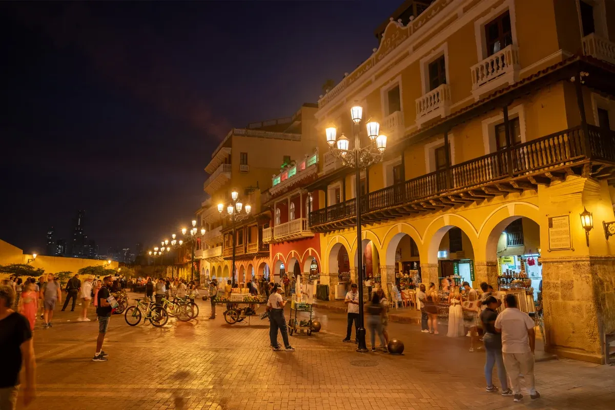Lamplit arcades of the Portal de los Dulces on Plaza de los Coches at night on a Cartagena, Colombia city guide